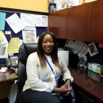 Ms. Jovan Moore at her desk in her office, smiling.